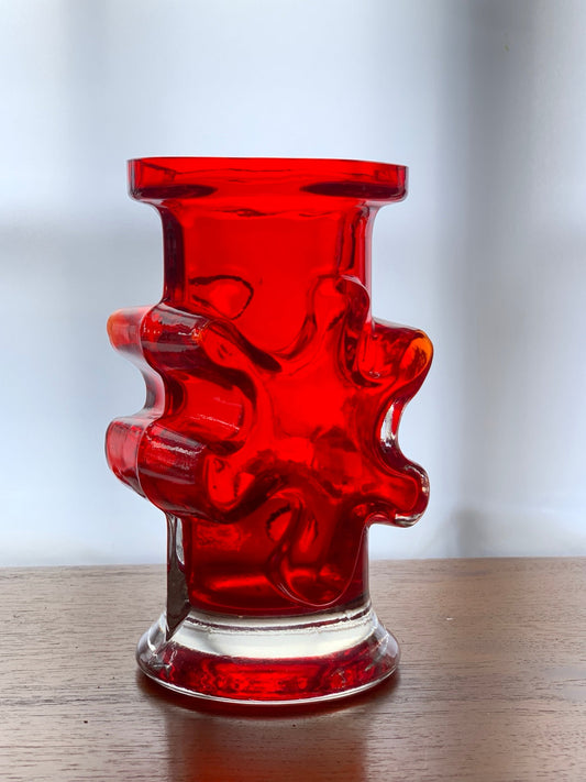 Red sculptural glass vase with deeply moulded circular forms.