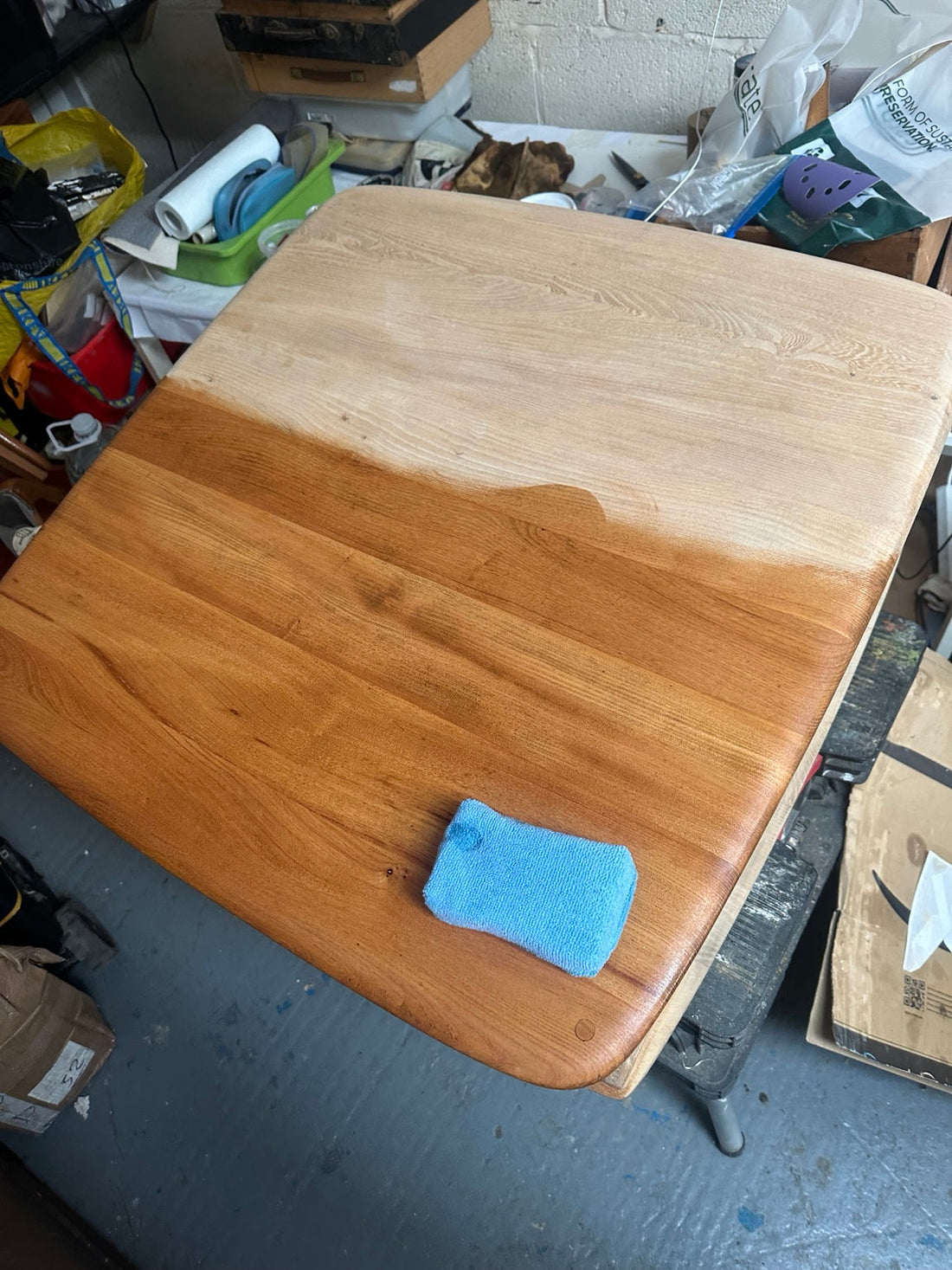 Ercol Pandora elm tabletop during conservation, showing the contrast between the untreated and revived surface.