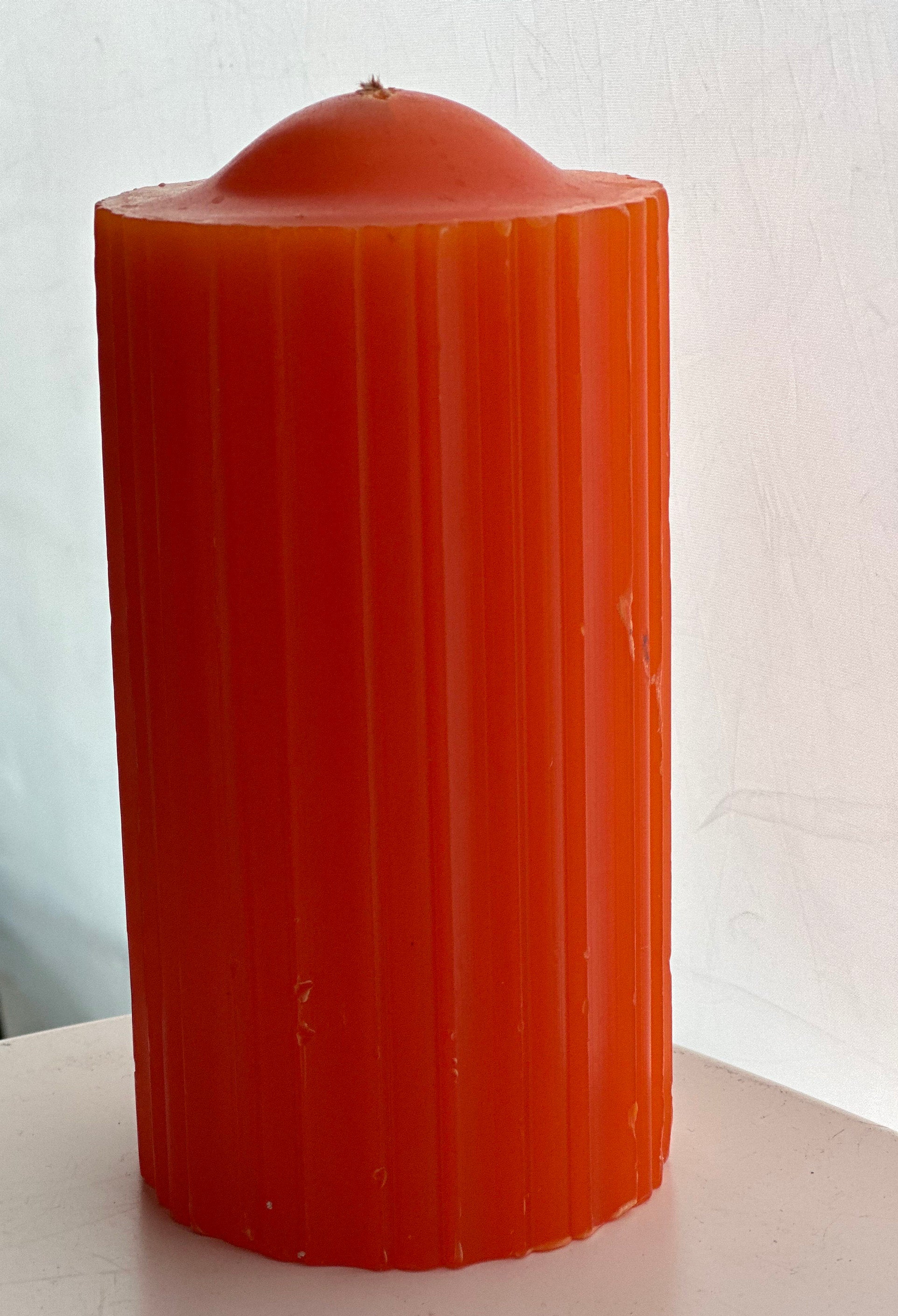 Orange wax pillar candle with ridged surface